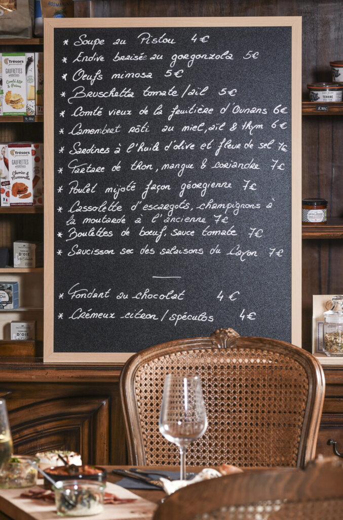 Menu écrit à la craie sur un tableau noir dans un cadre en bois, présentant une variété de tapas savoureux et gourmands