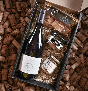 Coffret cadeau de vin proposé par Boîte à Cépages aux Avenières, comprenant une bouteille de vin et des produits du terroir.